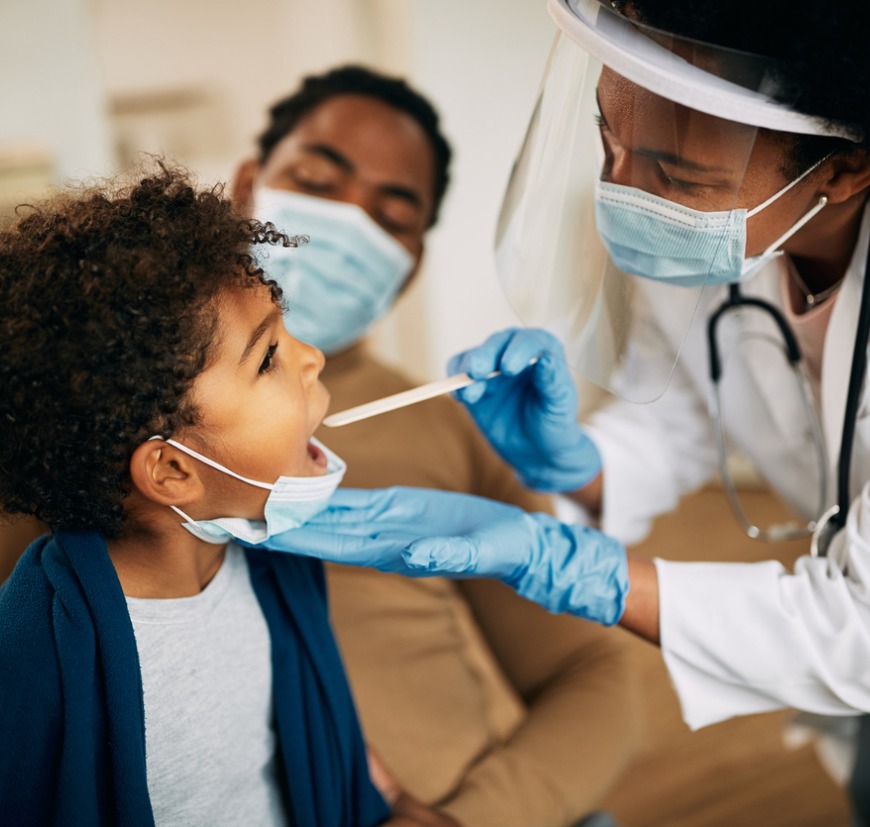 african american doctor with face mask examining boys throat